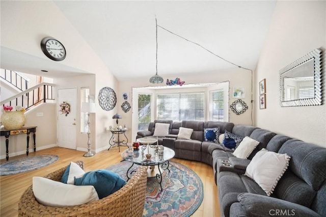 living area featuring baseboards, wood finished floors, high vaulted ceiling, and stairway
