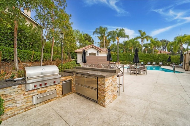 view of patio / terrace featuring a fenced in pool, area for grilling, exterior bar, and a grill