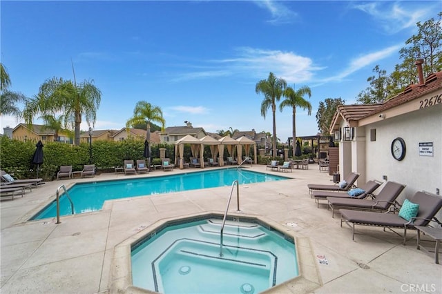 community pool featuring a residential view, a community hot tub, and a patio area