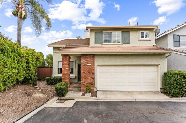 view of front of property with a tiled roof, driveway, a garage, brick siding, and stucco siding