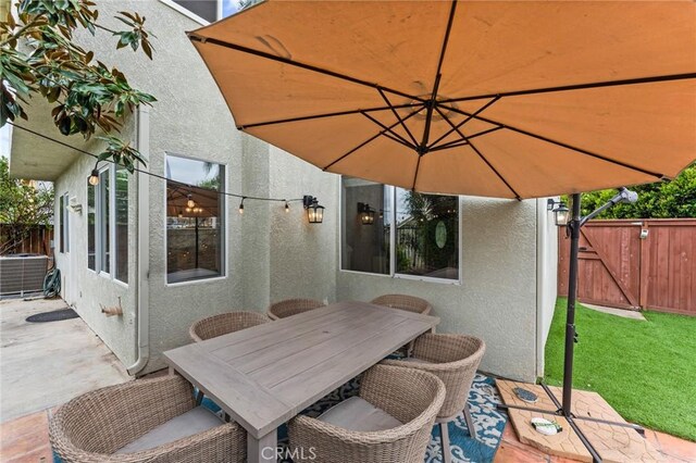 view of patio / terrace featuring fence, outdoor dining area, central AC, and a gate