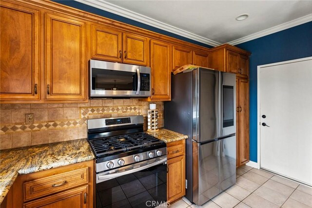 kitchen with stainless steel appliances, crown molding, decorative backsplash, and brown cabinets
