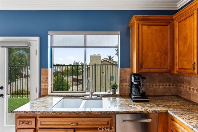 kitchen with brown cabinetry, stainless steel dishwasher, a sink, and tasteful backsplash