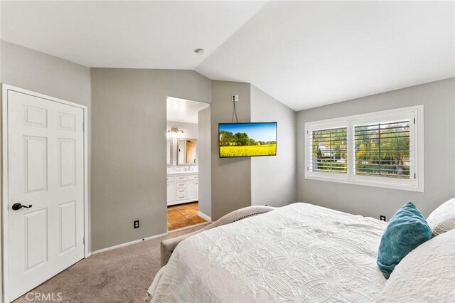 bedroom featuring vaulted ceiling, carpet floors, baseboards, and ensuite bathroom