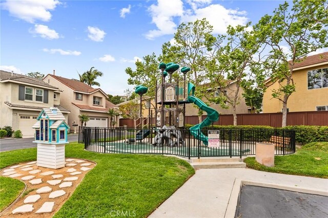 community jungle gym featuring a lawn, fence, and a residential view