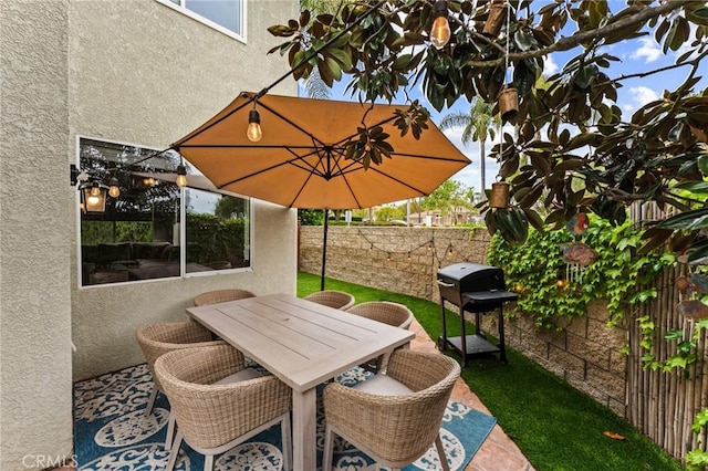 view of patio featuring fence, outdoor dining space, and a grill