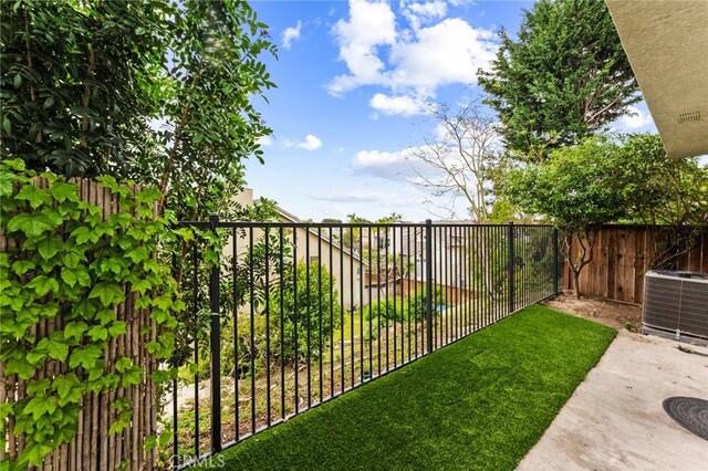 view of yard featuring a fenced backyard, central air condition unit, and a patio area