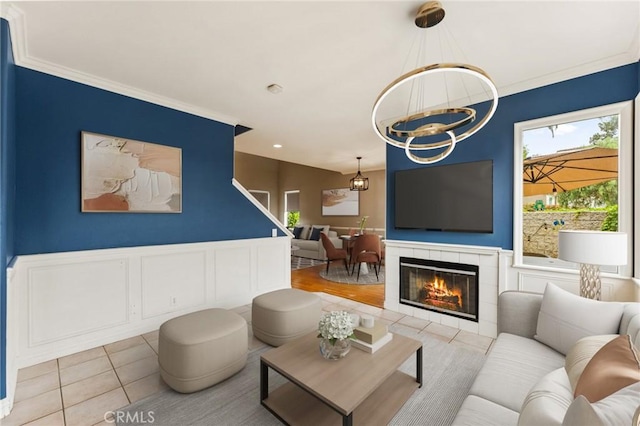 living area with ornamental molding, a notable chandelier, a wealth of natural light, and tile patterned floors