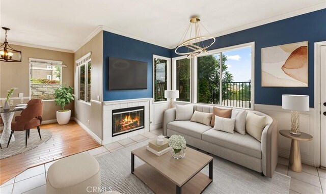 living area featuring a tiled fireplace, ornamental molding, and an inviting chandelier