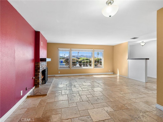 unfurnished living room featuring visible vents, baseboards, stone tile flooring, and a fireplace