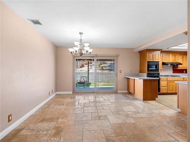 kitchen with black microwave, stone tile floors, light countertops, and baseboards