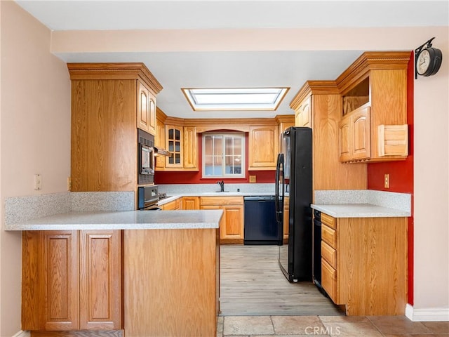 kitchen with light countertops, baseboards, black appliances, a peninsula, and glass insert cabinets
