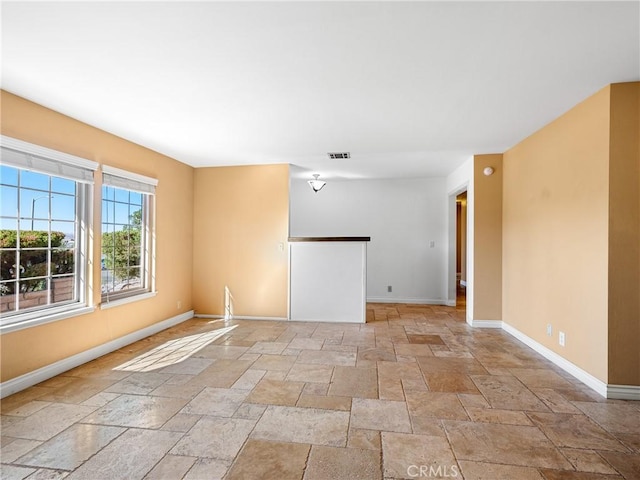 unfurnished room with stone tile floors, baseboards, and visible vents