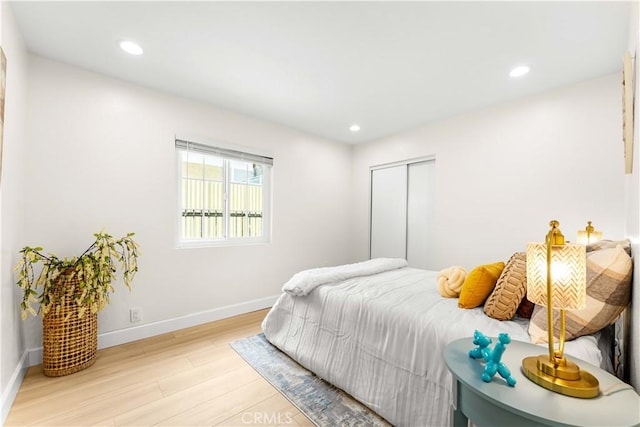 bedroom with wood finished floors, baseboards, recessed lighting, and a closet