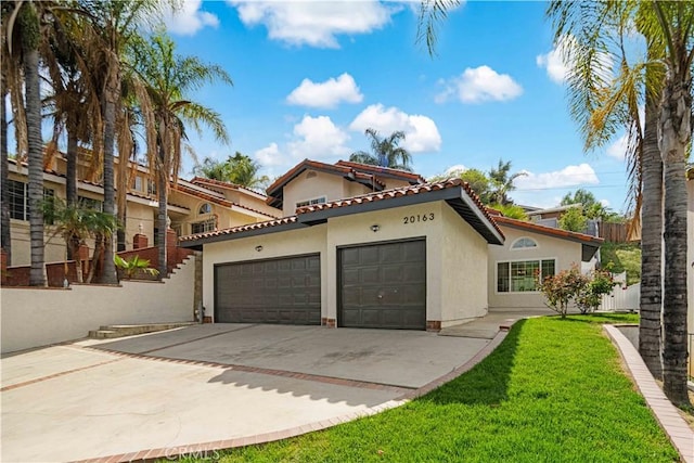 view of front of home featuring a front yard, stucco siding, a tiled roof, concrete driveway, and an attached garage