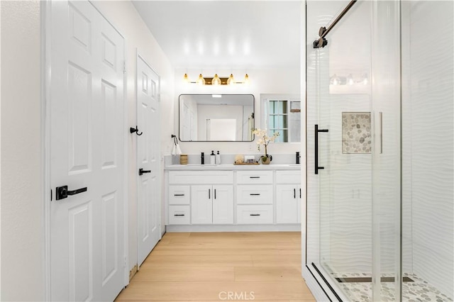 full bath featuring double vanity, wood finished floors, and a shower stall