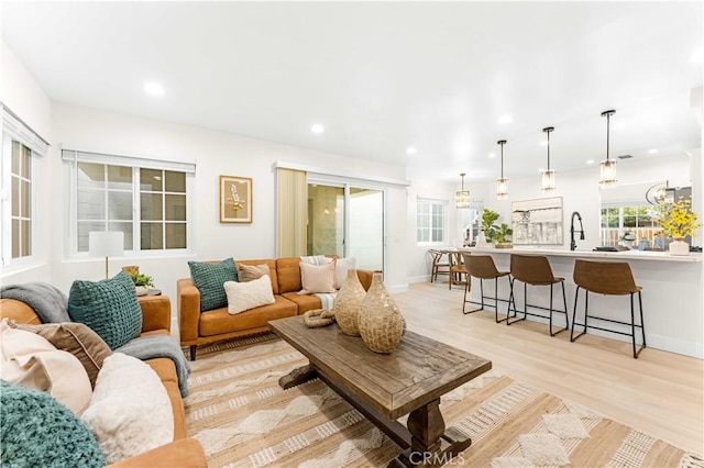 living area featuring baseboards, recessed lighting, and light wood-style floors