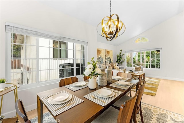 dining area with baseboards, high vaulted ceiling, a notable chandelier, and light wood finished floors