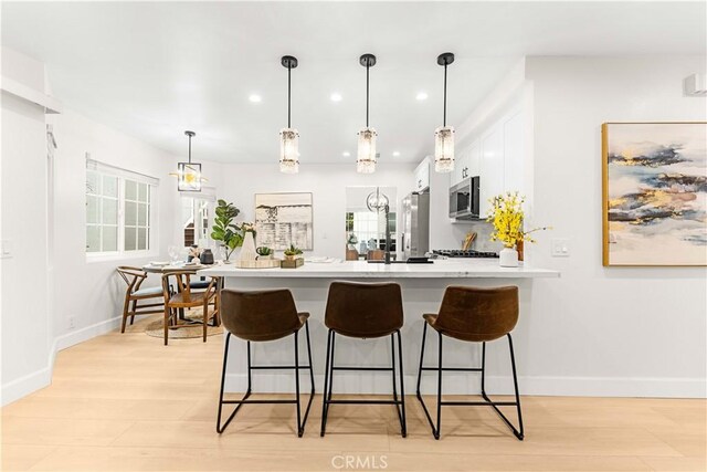 20163 Corona St, Corona, CA 92881 - kitchen featuring a peninsula, a kitchen bar, light countertops, white cabinetry, and recessed lighting