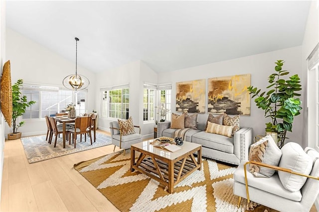 living room featuring lofted ceiling, a chandelier, and light wood-style floors