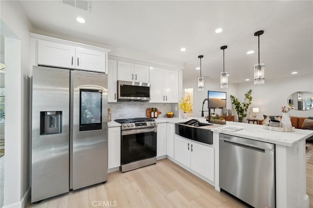 20163 Corona St, Corona, CA 92881 - kitchen featuring stainless steel appliances, a peninsula, a sink, decorative backsplash, and light wood finished floors