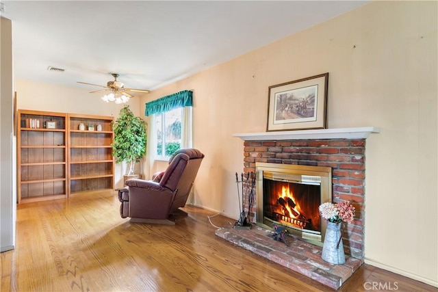 sitting room featuring a fireplace, wood finished floors, and ceiling fan