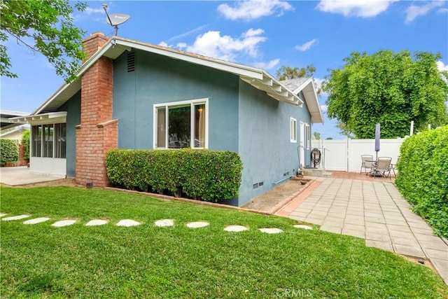 back of property with a chimney, fence, a patio area, a yard, and stucco siding