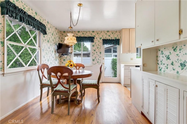 dining area with light wood-style floors, baseboards, and wallpapered walls