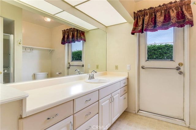 bathroom featuring vanity, a shower with shower door, and toilet