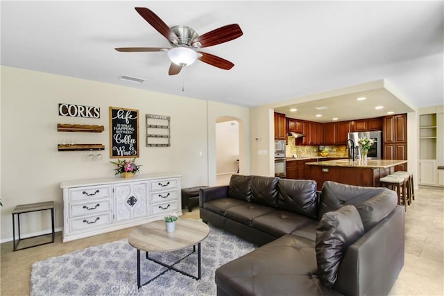 living room featuring ceiling fan, visible vents, arched walkways, baseboards, and recessed lighting