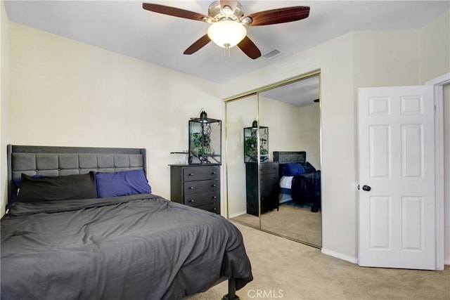 bedroom with visible vents, a closet, baseboards, light colored carpet, and a ceiling fan