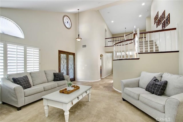 living area featuring visible vents, baseboards, high vaulted ceiling, light colored carpet, and arched walkways