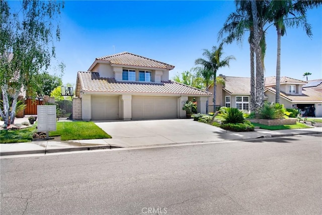 mediterranean / spanish-style house featuring a tile roof, a garage, fence, concrete driveway, and stucco siding