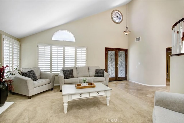 living area featuring light colored carpet, arched walkways, visible vents, and french doors