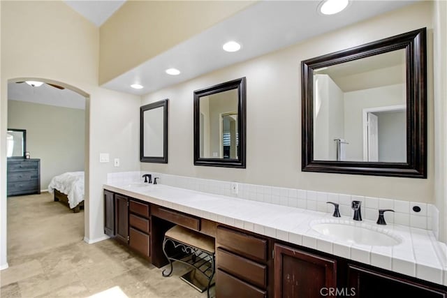 bathroom with a sink, baseboards, ensuite bathroom, and double vanity