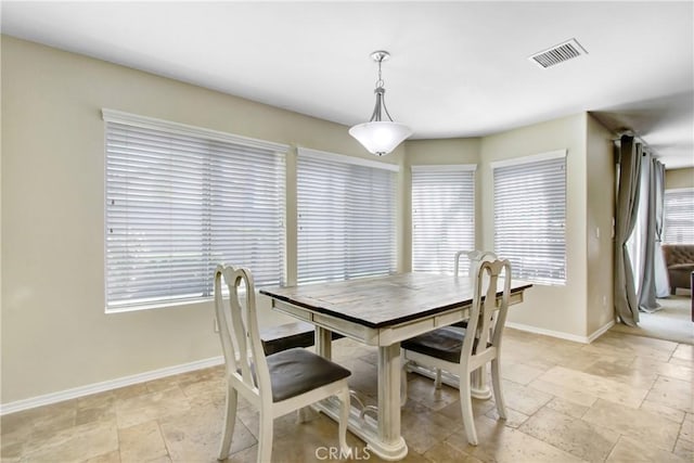 dining space with stone tile floors, baseboards, and visible vents