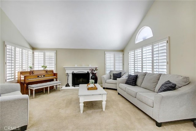 living area featuring a fireplace, high vaulted ceiling, plenty of natural light, and light carpet