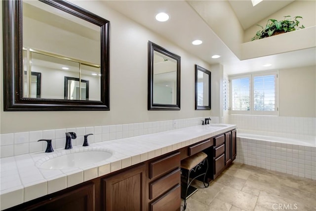 full bath with double vanity, recessed lighting, a sink, and a garden tub