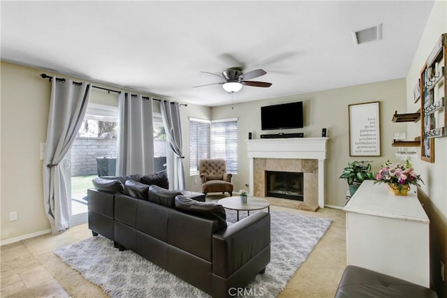 living room featuring visible vents, a ceiling fan, a tiled fireplace, and a healthy amount of sunlight