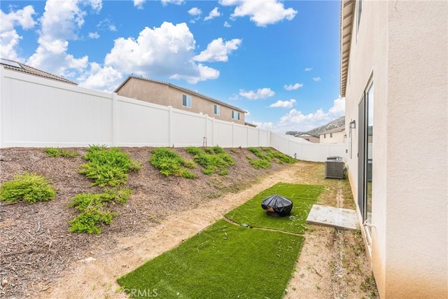 view of yard with a fenced backyard and central AC unit