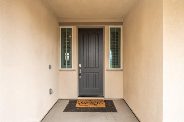 doorway to property featuring stucco siding