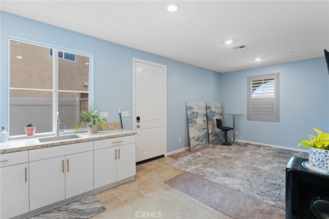 interior space featuring recessed lighting, baseboards, visible vents, and a sink