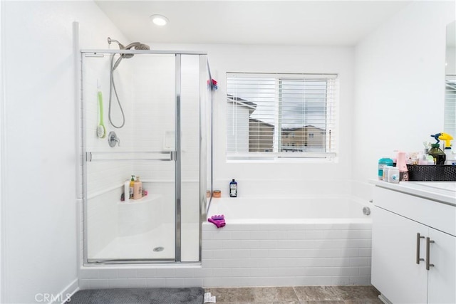 bathroom featuring a shower stall, a bath, and vanity