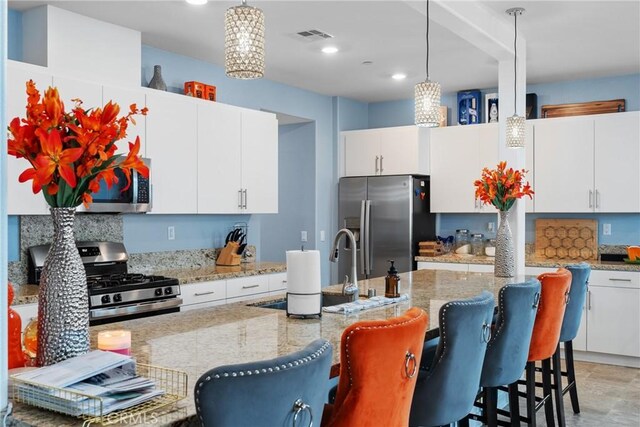 kitchen with pendant lighting, appliances with stainless steel finishes, a breakfast bar, and visible vents