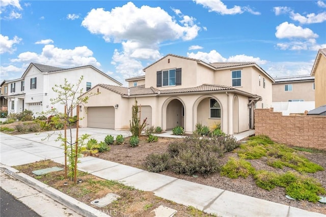 mediterranean / spanish home featuring fence, a tile roof, a garage, stucco siding, and concrete driveway