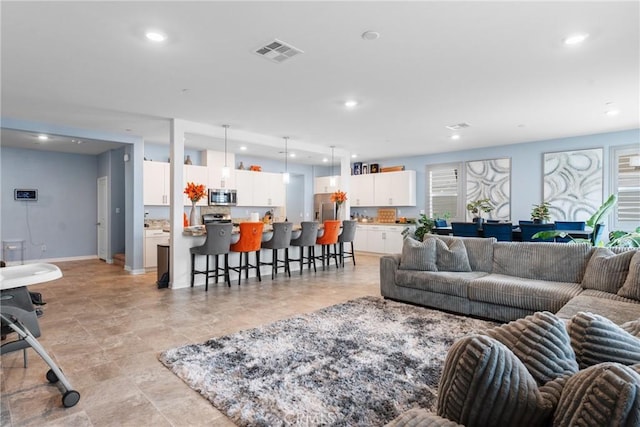 living area featuring baseboards, plenty of natural light, recessed lighting, and visible vents