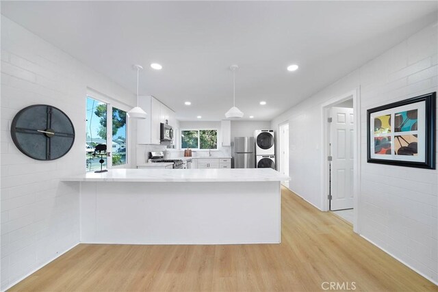 14816 Lanning Dr, Whittier, CA 90604 - kitchen featuring stacked washing machine and dryer, stainless steel appliances, white cabinets, a peninsula, and light countertops