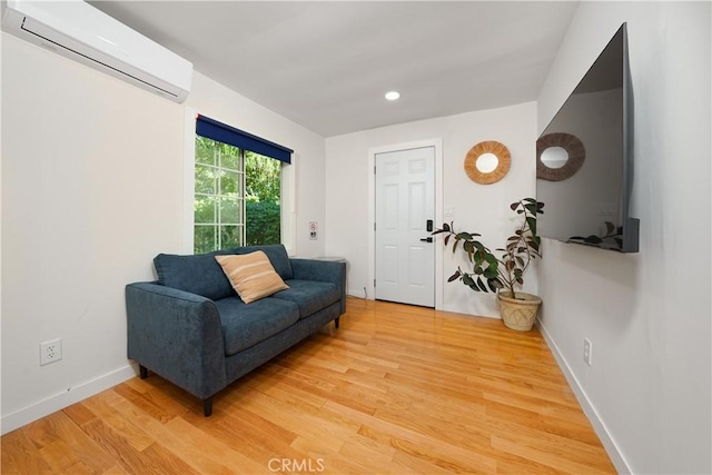 sitting room featuring an AC wall unit, baseboards, light wood finished floors, and recessed lighting