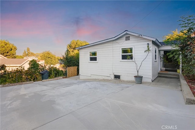 back of house at dusk featuring fence and a patio