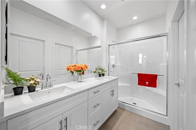 bathroom featuring tile patterned flooring, a sink, a shower stall, and double vanity
